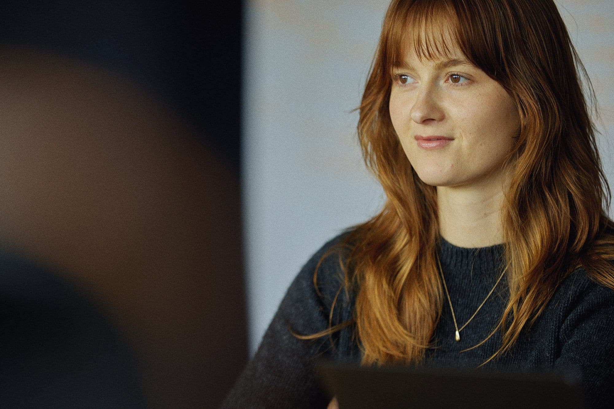A smiling team member in conversation, pencil in hand